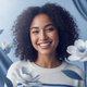 Close-up portrait of a smiling young woman with kind eyes, against a soft blue and white background.