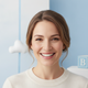 Headshot of a smiling parent in their late 20s to early 30s, looking at the camera with a warm, trustworthy expression.